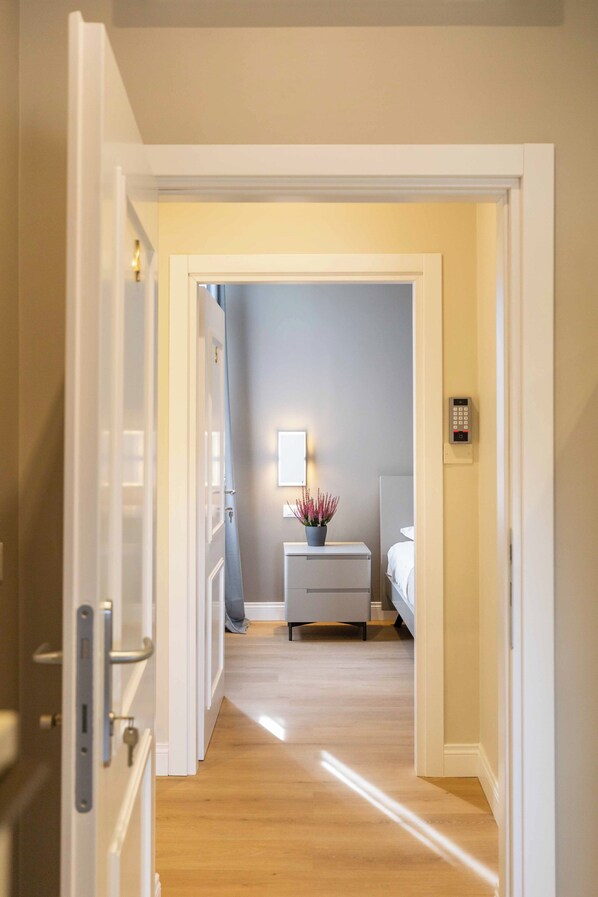 A hotel room with a wooden floor, a bedside table with a lamp, and a bed. - LUMINA3 Luxury Room Guest House, ROME (Rome)