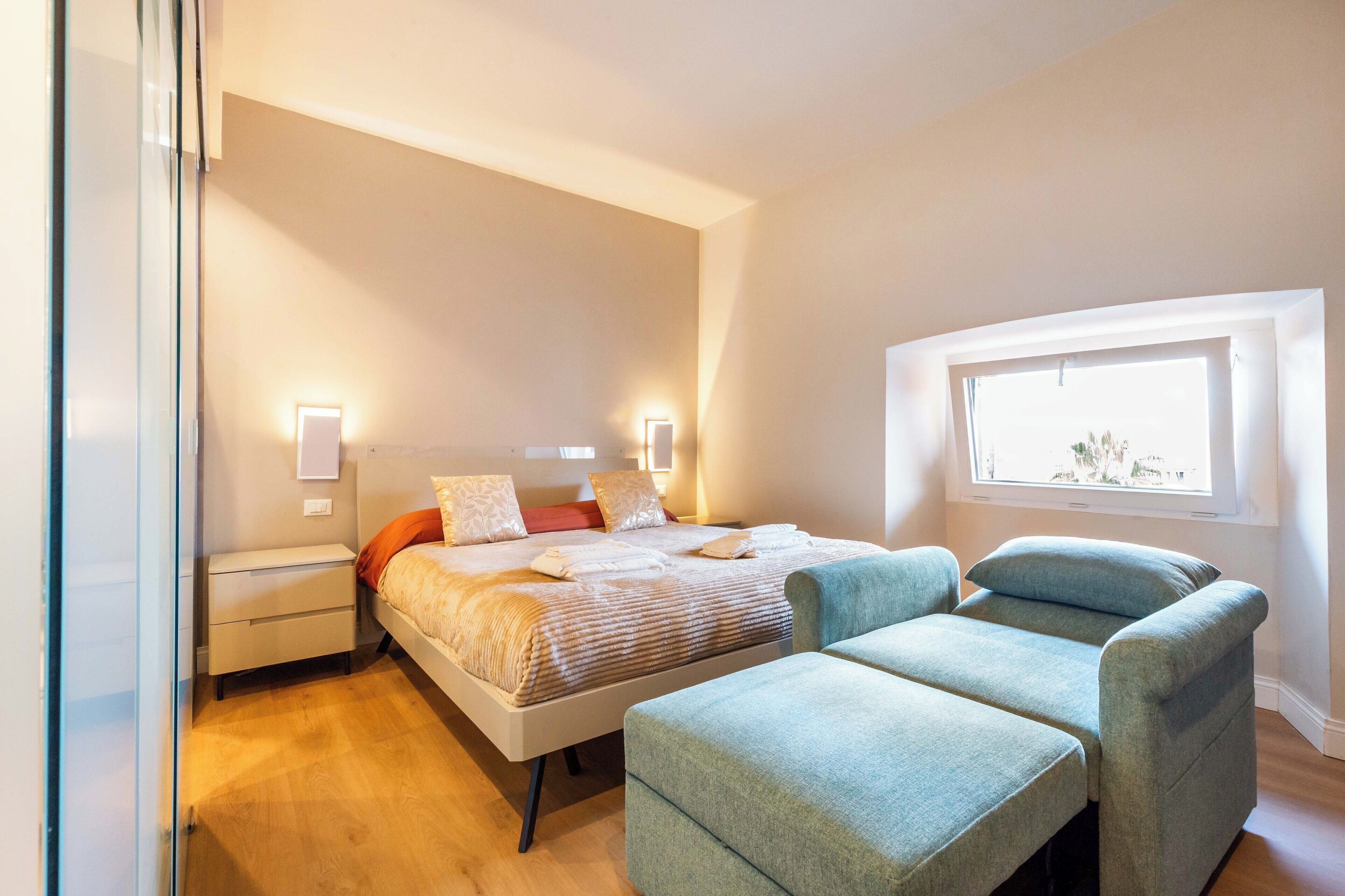 Ein modernes Schlafzimmer mit Bett, Nachttischen und einem Fenster.