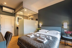 A modern hotel room with a large bed, a desk, and a bathroom visible through a glass partition. - LUMINA3 Luxury Room Guest House, ROME (Rome)