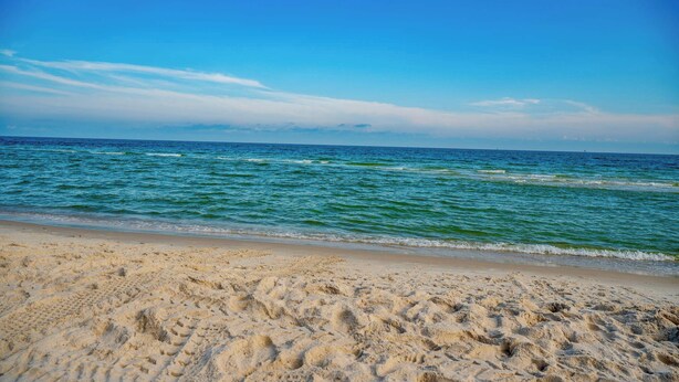 A sandy beach with gentle waves and a clear blue sky. - Angels Retreat @ Beach Club! (Gulf Shores)