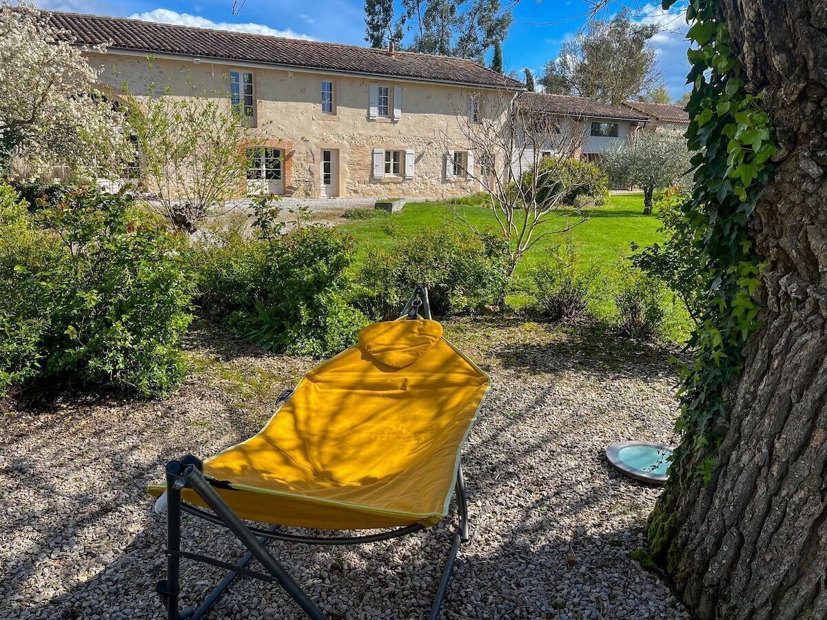 A yellow chair in a garden with a stone building in the background.