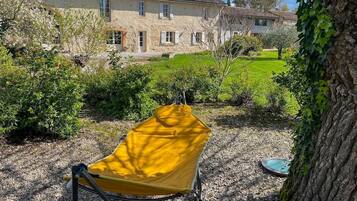 A yellow chair in a garden with a stone building in the background.