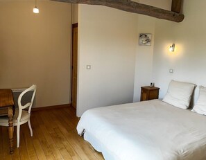 Une chambre à coucher avec un lit en bois, une chaise blanche, une petite table de chevet en bois et un luminaire fixé au mur.