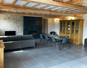 Un salon moderne avec une cheminée, un canapé, une table à manger avec des chaises et un buffet en bois.