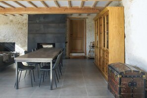 A dining area with a long wooden table and chairs, a wooden cabinet, and a vintage suitcase. - 3-star holiday cottage in a barn with swimming poo (Fiac)