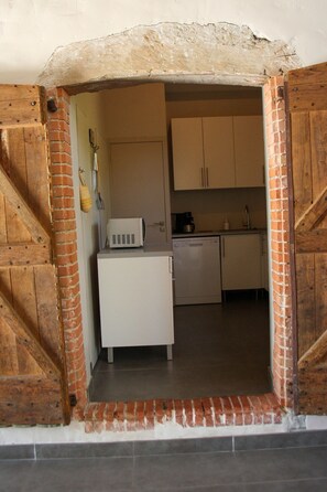 Cocina compacta con armarios blancos, microondas y cafetera.