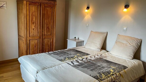 Ein Schlafzimmer mit einem großen Bett, einem Holzschrank, Nachttischen und Wandleuchten.