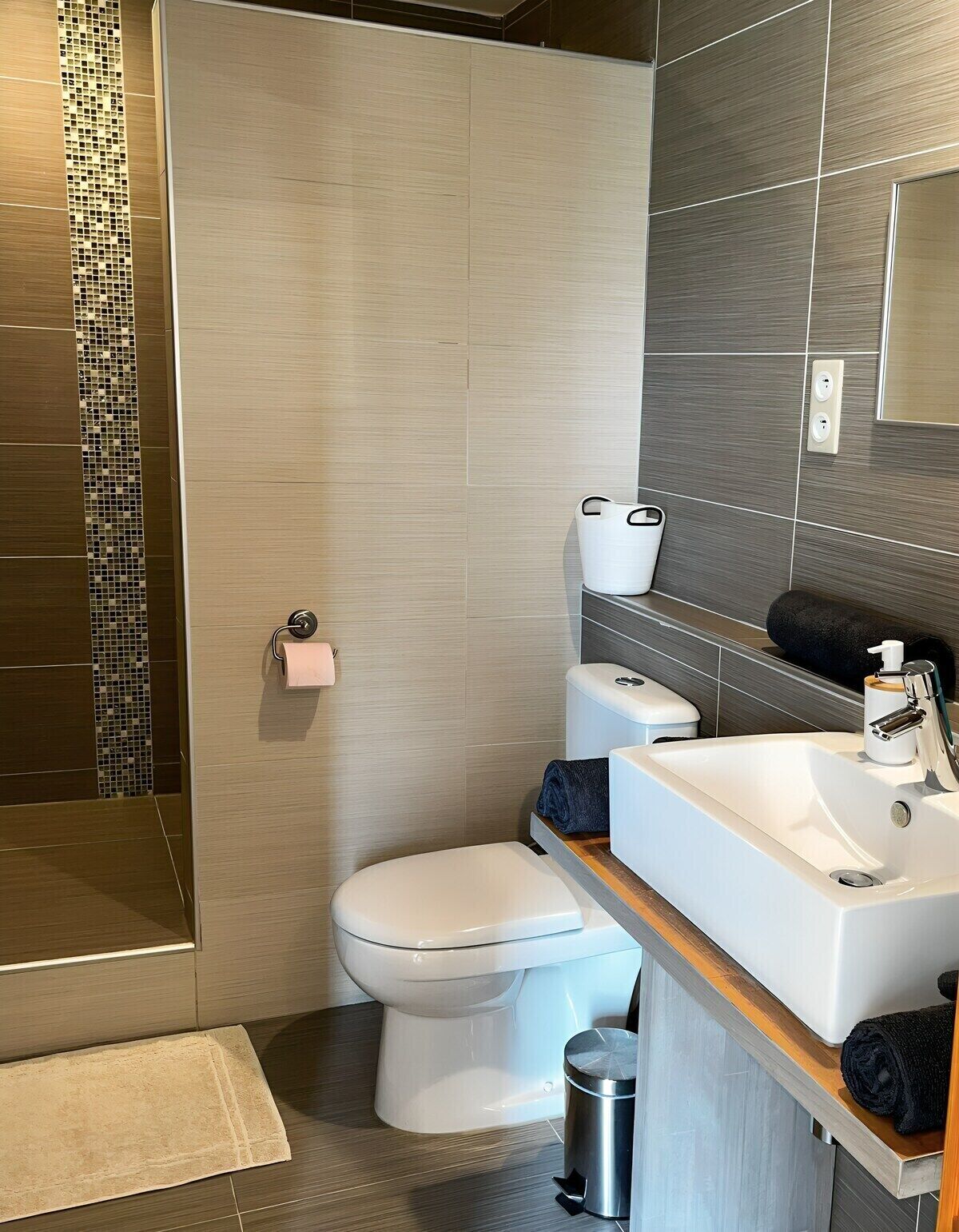 Une salle de bain moderne équipée d’une douche, de toilettes, d’un lavabo et d’un miroir.