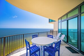 A balcony with a table and chairs, overlooking a body of water.