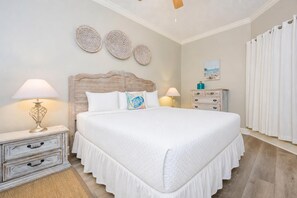 A bedroom with a large bed, two bedside tables with lamps, a dresser, and a wall with three decorative plates.