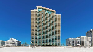 A tall hotel with multiple balconies, located on a beach with other buildings nearby. - Beach Front, Upscale 27th Floor - Phoenix West 2704, 3 bedroom, New Rental! (Orange Beach)