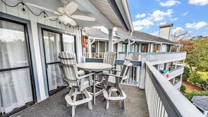 A balcony with a table and chairs, a ceiling fan, and a view of the surrounding area. - Gorgeous modern condo with unmatched view looking out over the pool! (Surfside Beach)