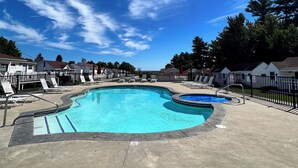 A swimming pool with lounge chairs and a hot tub, surrounded by a fence and houses. - The Nautical Nest-Belle of Maine (Wells)