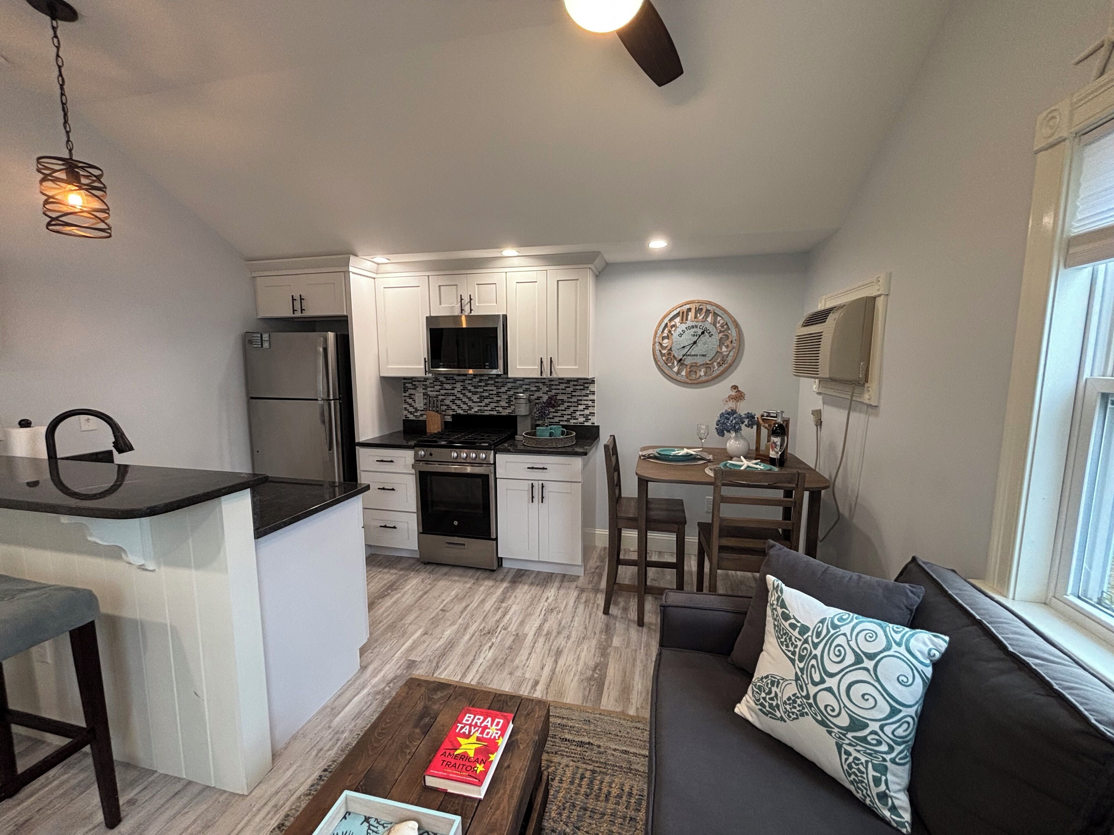 A compact living space with a kitchenette, a dining area, and a seating area with a sofa and a coffee table.