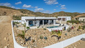 A modern house with a pool, surrounded by a rocky garden and desert landscape.