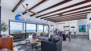 A modern living room with a large sofa, coffee table, and a view of the ocean.