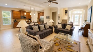 A spacious living room with two sofas, a patterned armchair, a coffee table, and a ceiling fan. - 4/3 Canal Front Condo, Private Pool, Dock (Longboat Key)