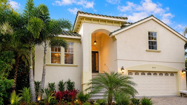 A single-story house with a garage, a covered entryway, and a well-maintained garden with various plants. - 4/3 Canal Front Condo, Private Pool, Dock (Longboat Key)