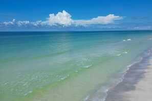 Ein Strand mit klarem türkisblauem Wasser und sandigem Ufer.
