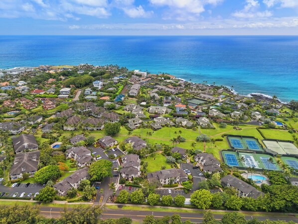Vista aérea de una zona residencial costera con casas, áreas verdes y una vista despejada del océano.