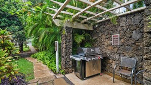 Un patio al aire libre con un muro de piedra, una parrilla y una silla.