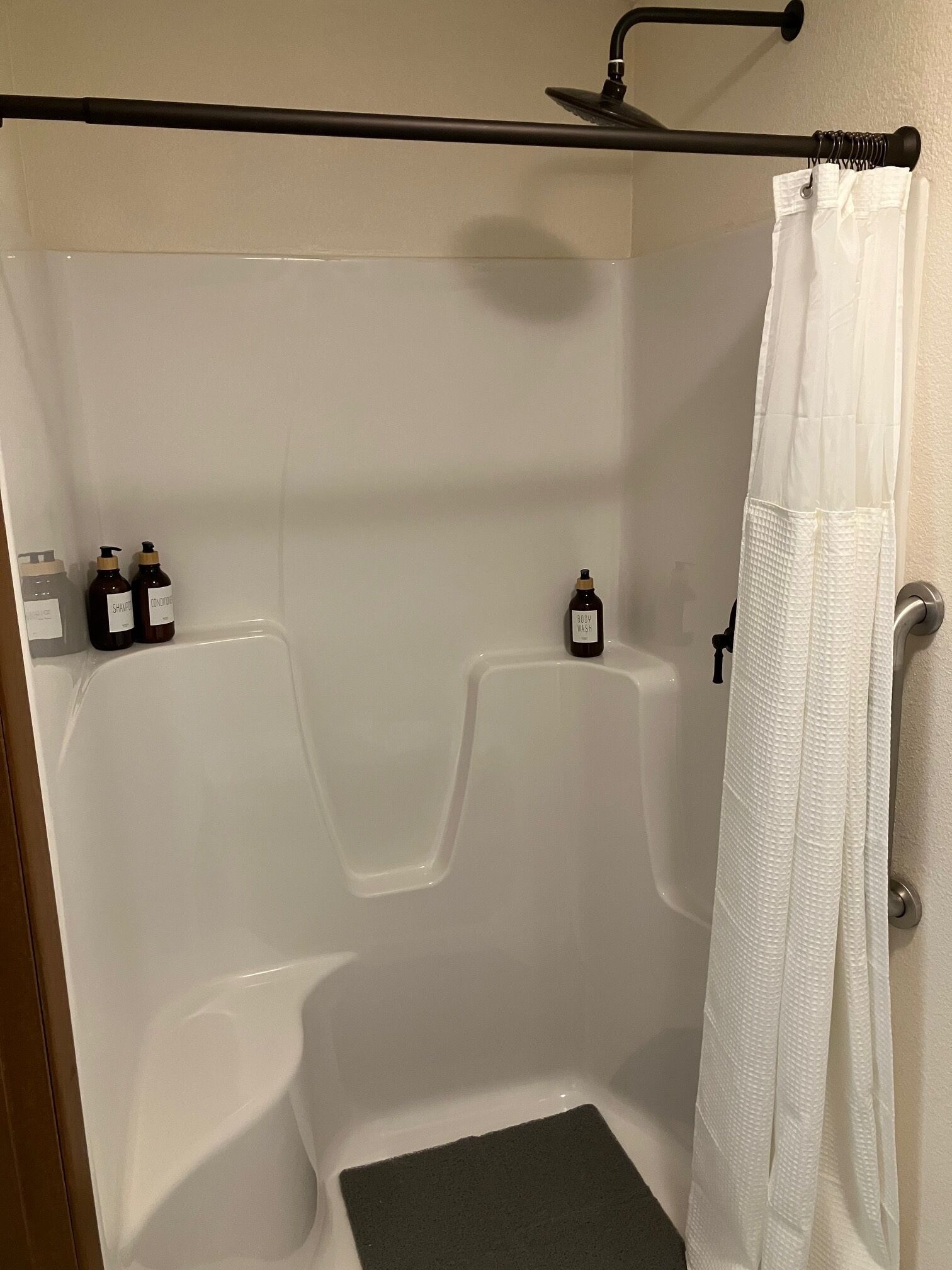 A shower area with a bathtub, a showerhead, and bottles of shampoo and body wash.
