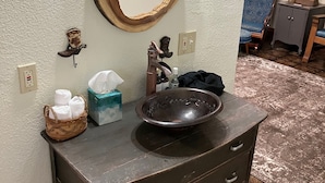 Une salle de bain avec un meuble-lavabo en bois, un grand miroir, un évier et un porte-serviettes.