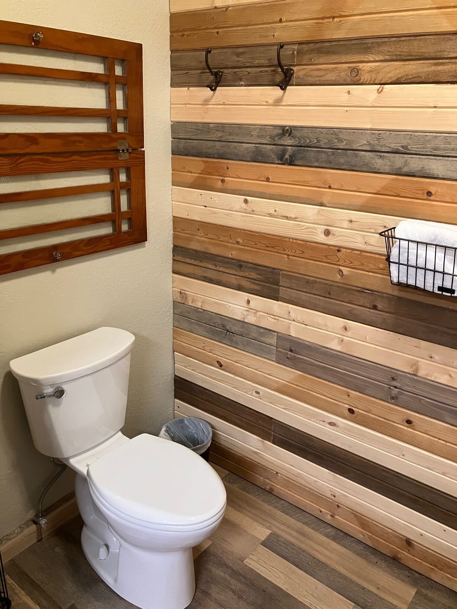 A bathroom with a wooden slat wall, a toilet, and a towel rack.