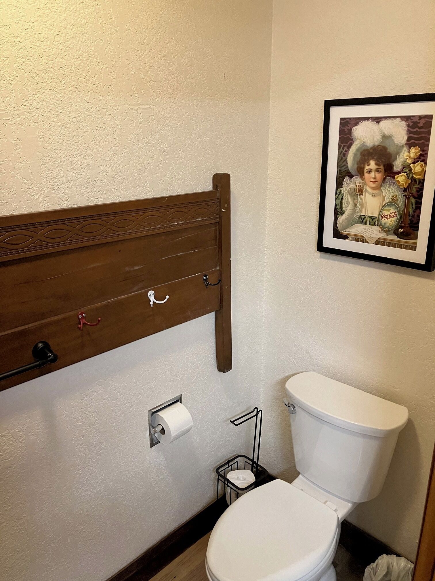 A bathroom with a wooden vanity, a toilet, a framed picture on the wall, and a roll of toilet paper on the wall.