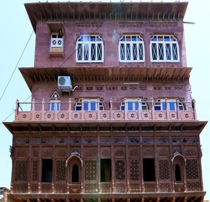 A multi-story building with ornate balconies, large windows, and intricate architectural details. - Chanod Haveli (Jodhpur)