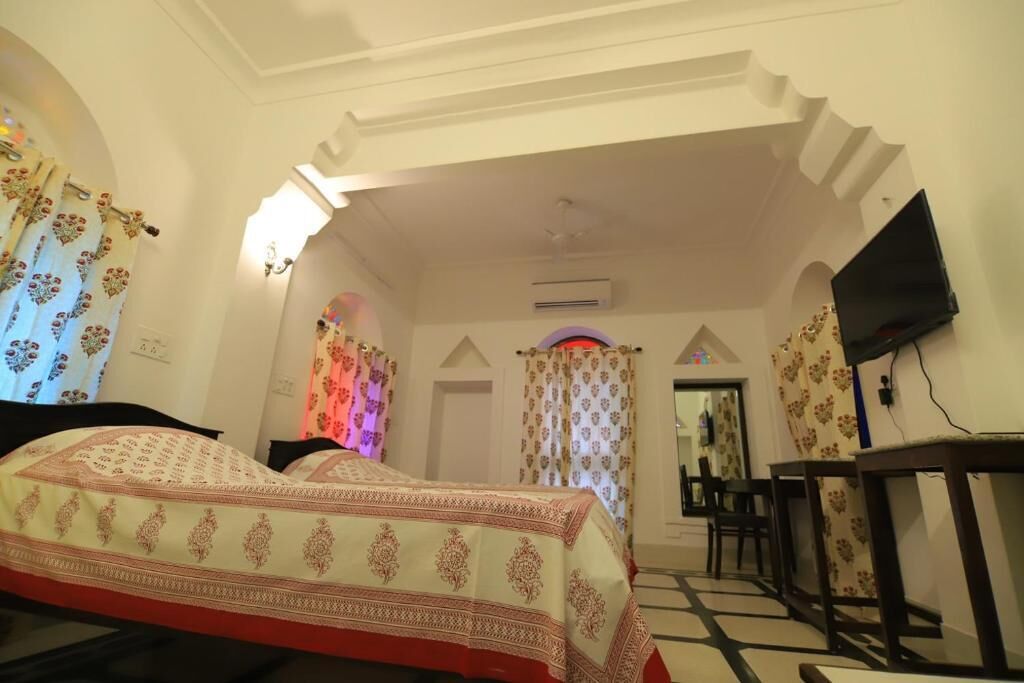 Una habitación de hotel con cama, escritorio, televisión y vista al pasillo.