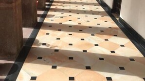 A corridor with patterned flooring, a central archway, and potted plants. - Chanod Haveli (Jodhpur)