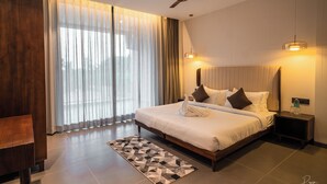 A modern hotel room with a large bed, a ceiling fan, a bedside table, and a nightstand. - Hotel Omaya Garden (Raipur)