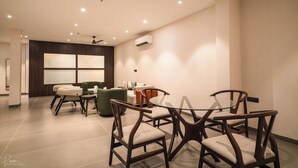 A modern dining area with a glass table, wooden chairs, and a ceiling fan. - Hotel Omaya Garden (Raipur)