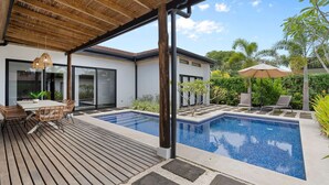 Una casa moderna con piscina, mobili da esterno e una pergola.