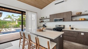 Una cucina moderna con isola centrale, sgabelli da bar, piano cottura integrato e forno a microonde.