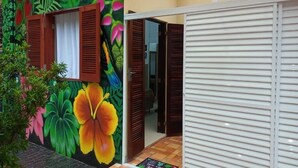 A room with a vibrant floral mural, wooden shutters, and a tiled floor.