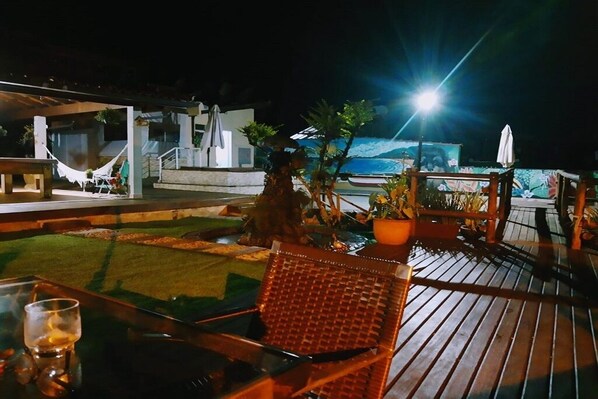 An outdoor seating area with a table and chairs, a hammock, and a view of the ocean.