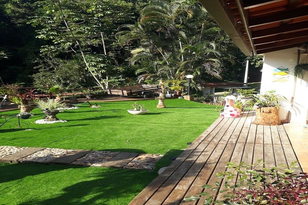 A well-maintained garden with artificial grass, various potted plants, and a wooden deck.