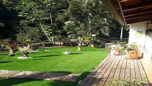 A well-maintained garden with artificial grass, various potted plants, and a wooden deck.