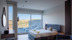 Un dormitorio moderno con una cama grande, un escritorio y un balcón con vistas al desierto.