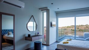 Habitación de hotel moderna con una cama grande, tocador integrado, espejo redondo y balcón con vistas al campo.