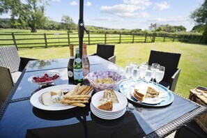 An outdoor dining table set with plates of food, glasses, and bottles. - WIllersey Farmhouse, Sleeping 8 people. (Broadway)
