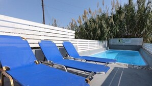 A pool area with blue lounge chairs and a sign for 'Backpackers Taco'. - Fira Backpackers Place (Santorini)