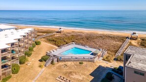 A beachfront hotel with a swimming pool, multiple balconies, and a beach access area. - Condo in Duck with Ocean Views, Community Amenities (Duck)