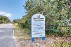 A sign for Ocean Sands Private Community stating private roads, beach access for owners and guests only, no on-street parking, towing enforcement, fireworks and bonfires prohibited, and no soliciting. - Oceanside Top Level Condo w/ Pool Views in Corolla (Corolla)