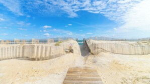 A beach with a wooden boardwalk leading to the water, surrounded by sand dunes and a wooden fence. - Oceanfront first-floor condo in Rodanthe (Rodanthe)