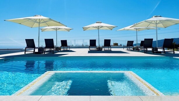 A pool with clear blue water, surrounded by lounge chairs and umbrellas, with a clear sky in the background. - Casa Vista Mar 2 Los Laureles (El Paso)
