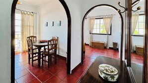 A dining area with a wooden table and chairs, an arched doorway, and a window with curtains. - Casa Vista Mar 2 Los Laureles (El Paso)