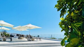 A terrace with white umbrellas, lounge chairs, and steps leading to a pool area. - Casa Vista Mar 2 Los Laureles (El Paso)
